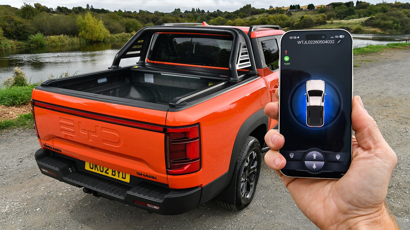 Smartphone μπροστά από BYD Shark με ηλεκτρικό συρόμενο κάλυμμα καρότσας.