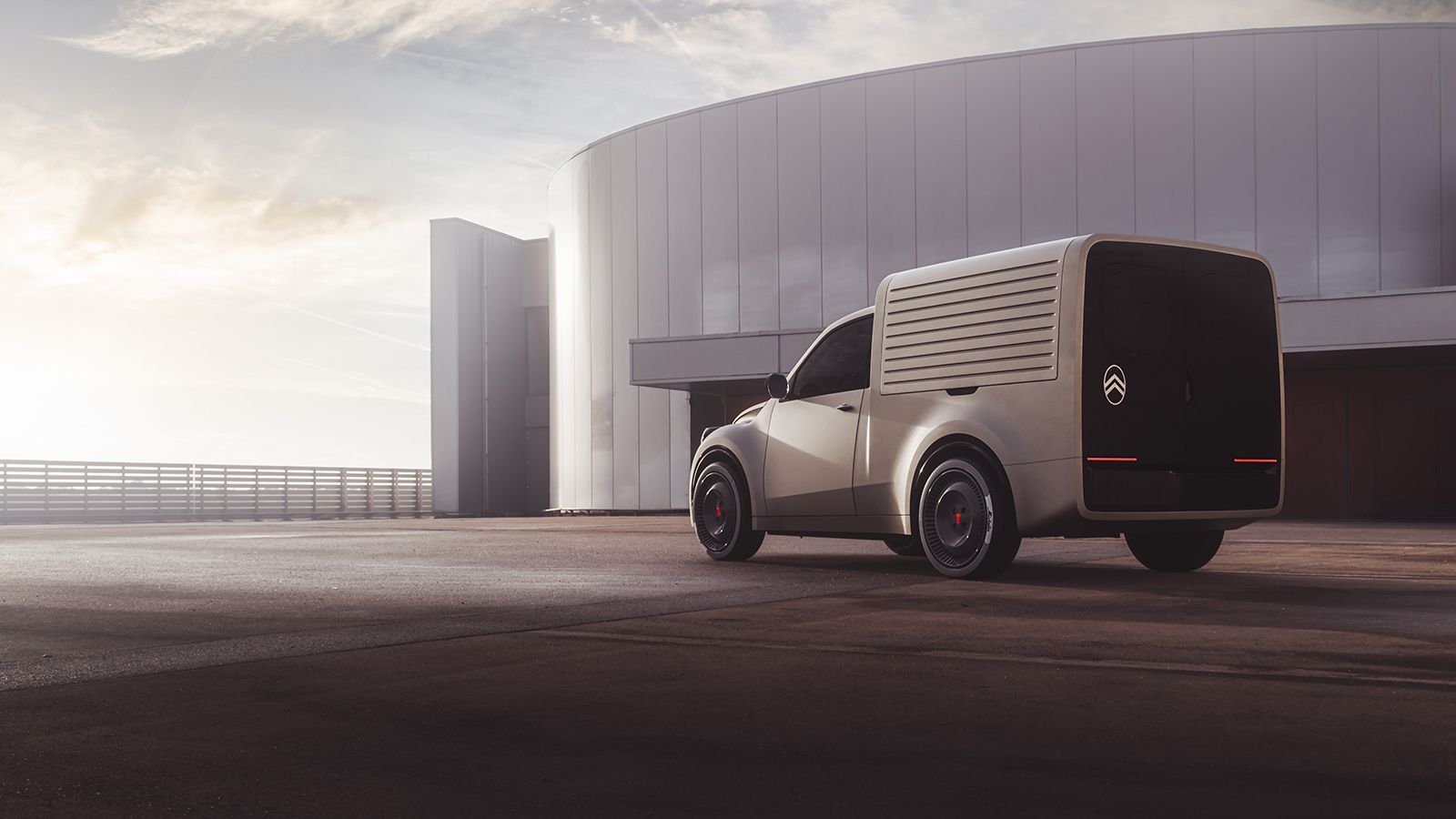 Πίσω τρία τέταρτα άποψη του λευκού Citroen 2CV Fourgonnette concept van σταθμευμένου έξω από σύγχρονο κτίριο κατά το ηλιοβασίλεμα.