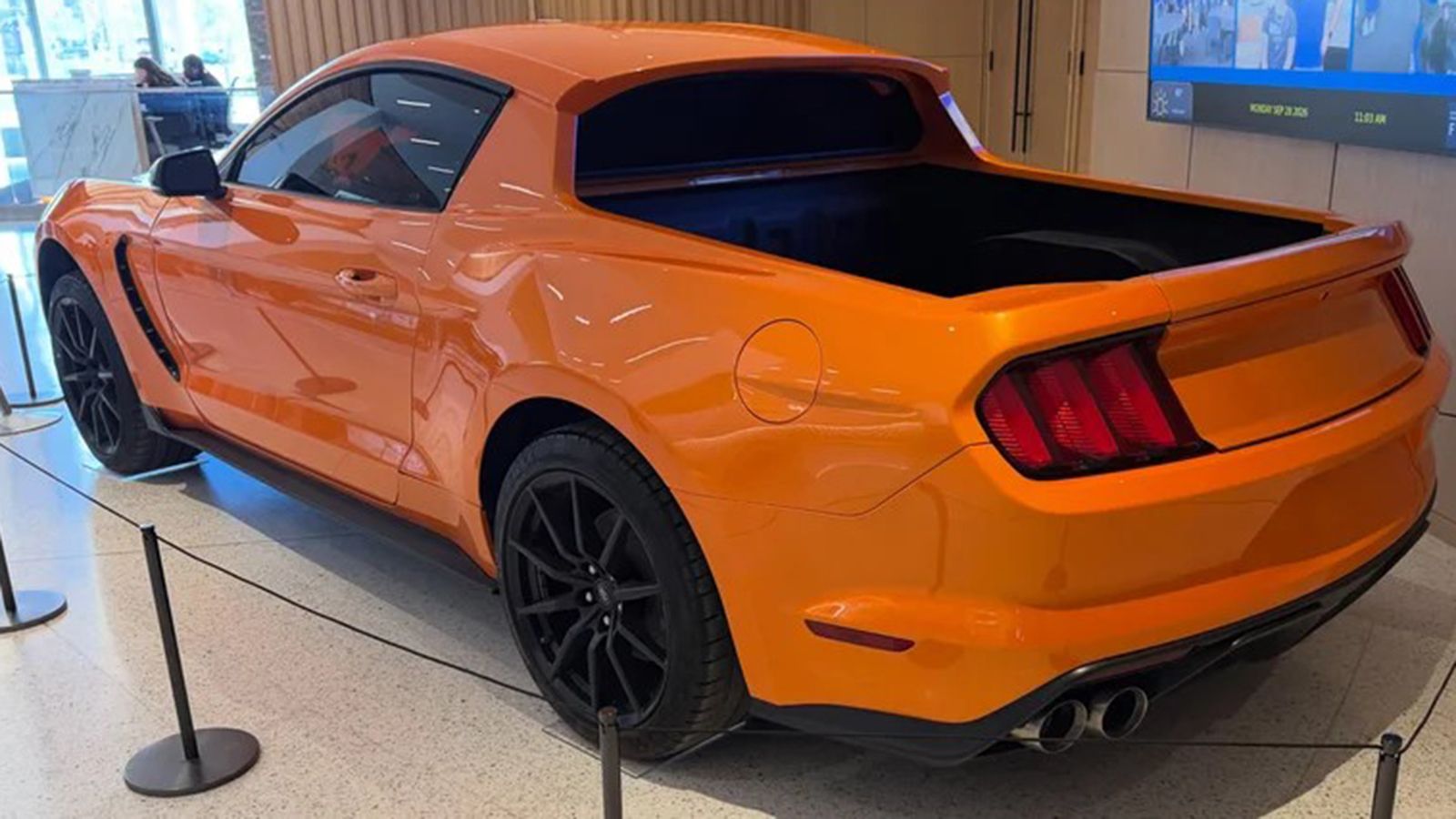 Πορτοκαλί Ford Mustang Pick-Up από πίσω αριστερά, με ανοιχτή καρότσα και μαύρες ζάντες.