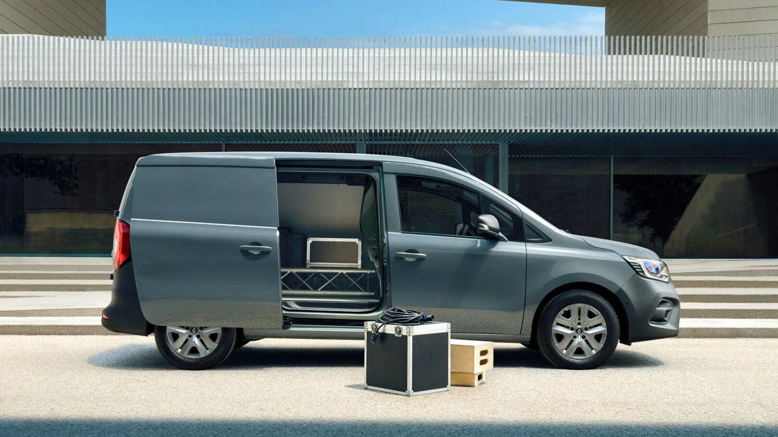 Ασημί Renault Kangoo Van με ανοιχτή πλαϊνή συρόμενη πόρτα και κιβώτια επαγγελματικού εξοπλισμού στον χώρο φόρτωσης και στο έδαφος.