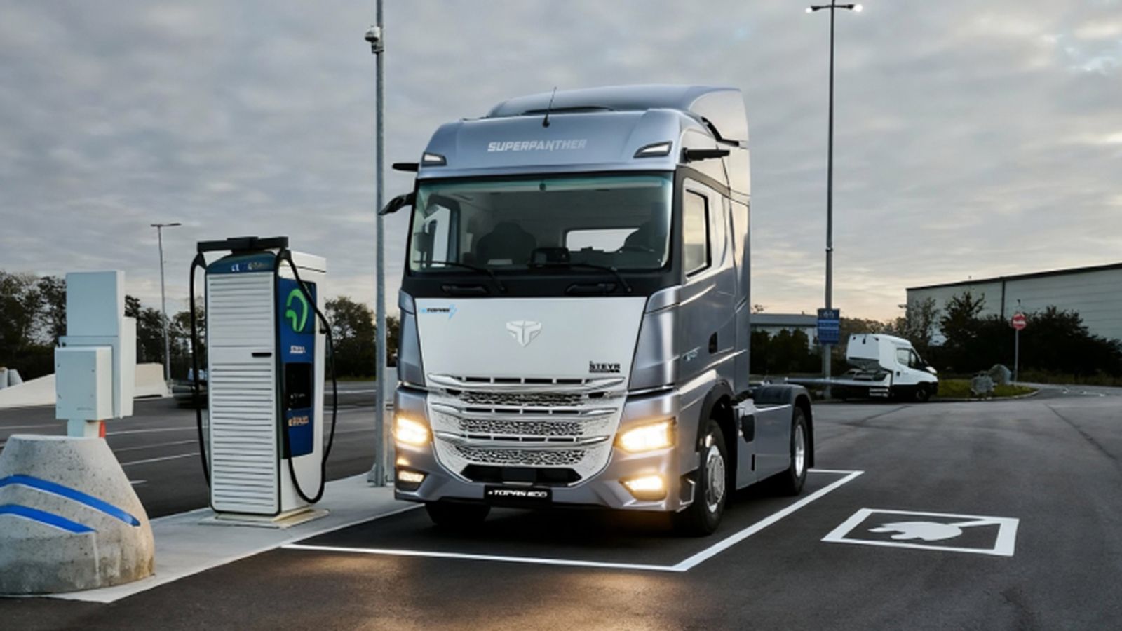 Ηλεκτρικό φορτηγό SuperPanther eTopas 600 σταθμευμένο δίπλα σε ταχυφορτιστή.