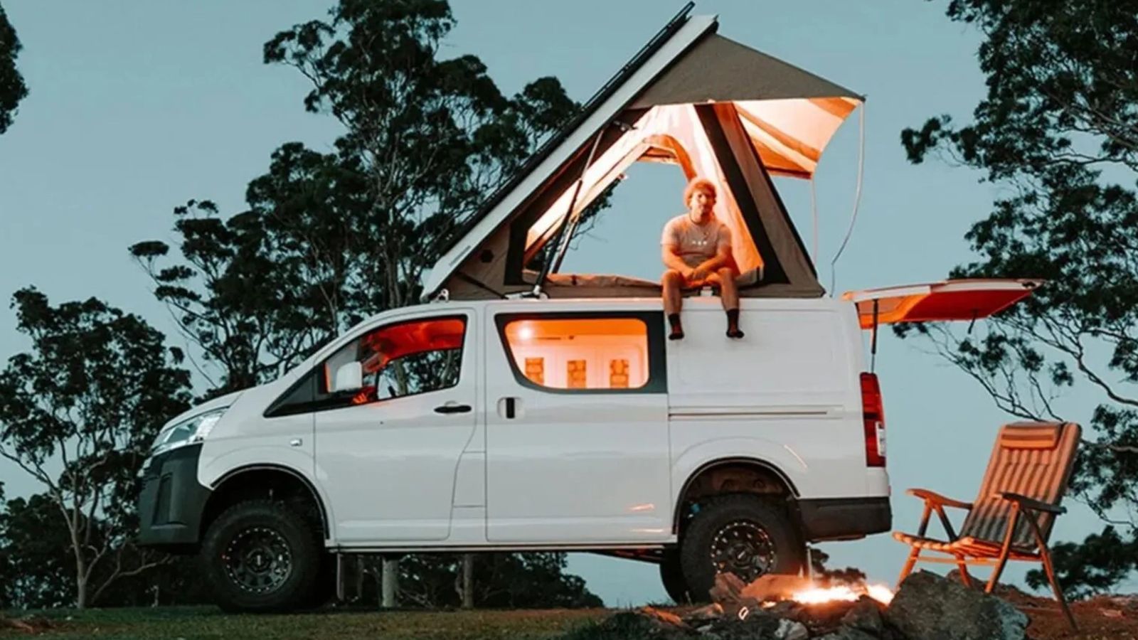 Toyota HiAce Camper με ανοιχτή αναδυόμενη οροφή σε χώρο κατασκήνωσης.
