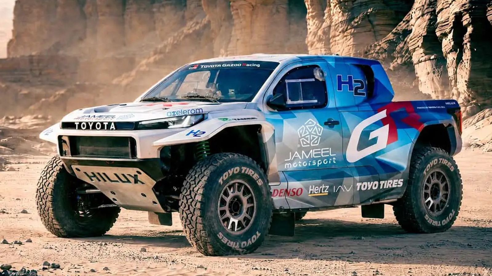 Toyota Hilux υδρογόνου DKR GR FC σε έρημο, με αγωνιστικά ελαστικά και χρώματα GAZOO Racing.